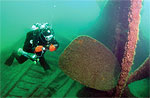 Diver inspecting four-bladed steel propeller.