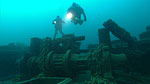 Divers above bow windlass wrapped with anchor chain.
